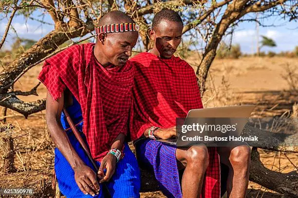 The image features Maasai Men operating a laptop