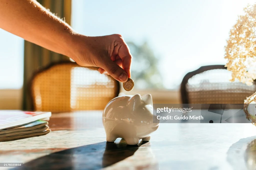 Woman putting savings in a white piggy bank.